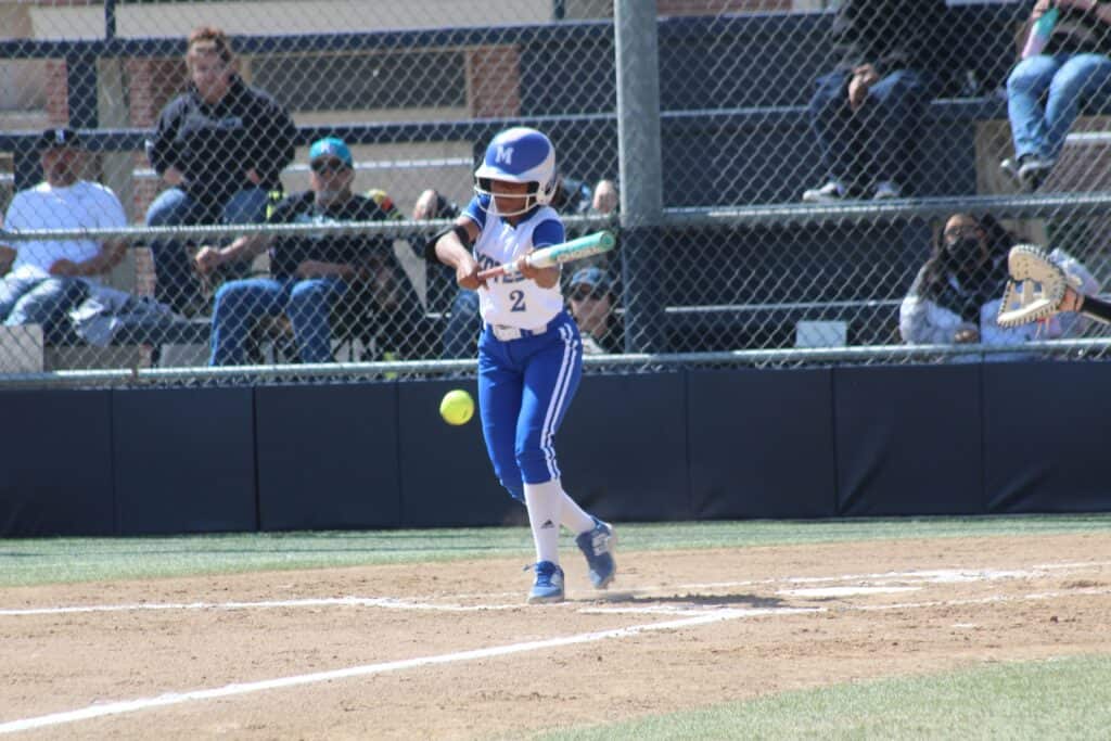 Young baseball player swinging at a pitch during a game.