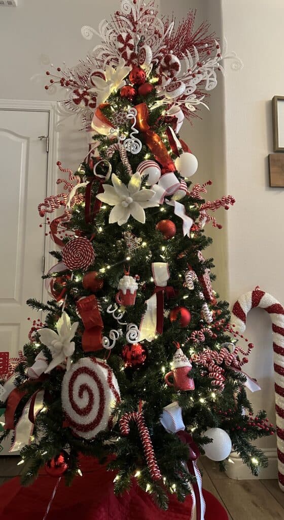 Decorated Christmas tree featuring red, white, and gold ornaments, ribbons, and lights for holiday c.