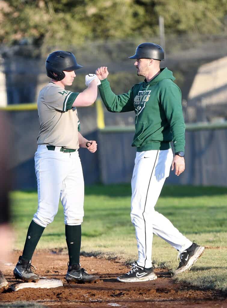 Madera baseball player and coach fist bump on the field.