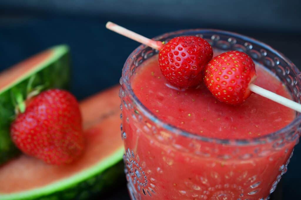 Refreshing strawberry watermelon smoothie in a glass with fresh fruit garnish.