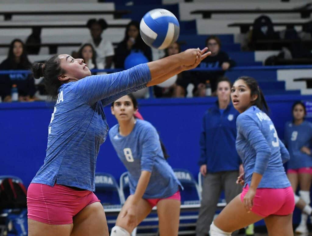 Volleyball player preparing to serve during a match.