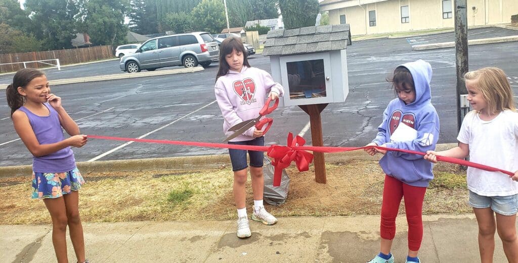 Children participating in a ribbon-cutting ceremony outside Madera community building.