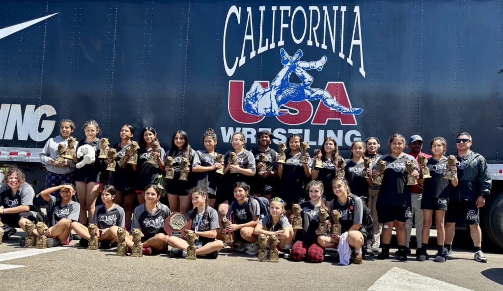 Madera wrestling team posing with medals in front of California USA Wrestling banner.