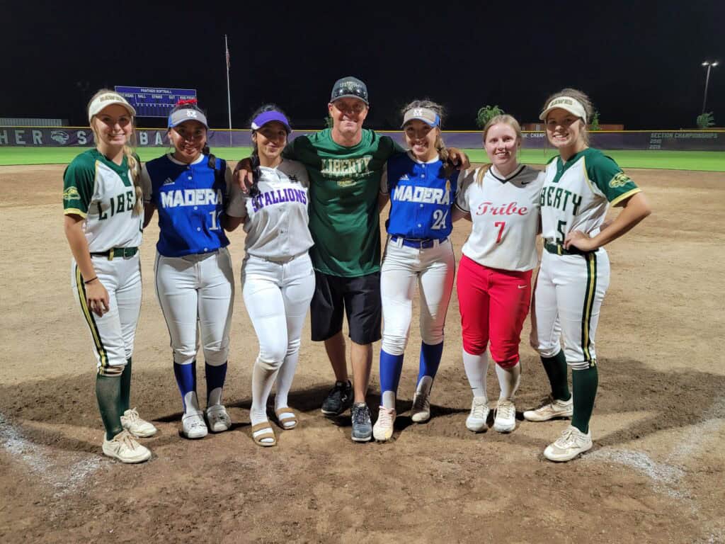 Softball team from Madera High School with coach after game at night.