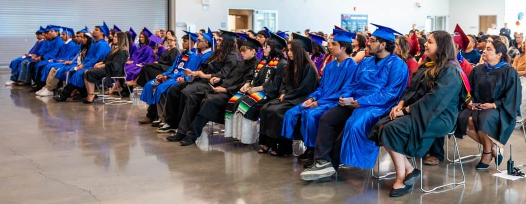 Students in caps and gowns attending graduation ceremony at Madera High School.