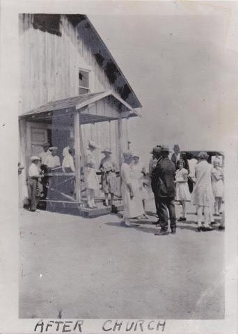 Old black-and-white photo of people outside a church building.