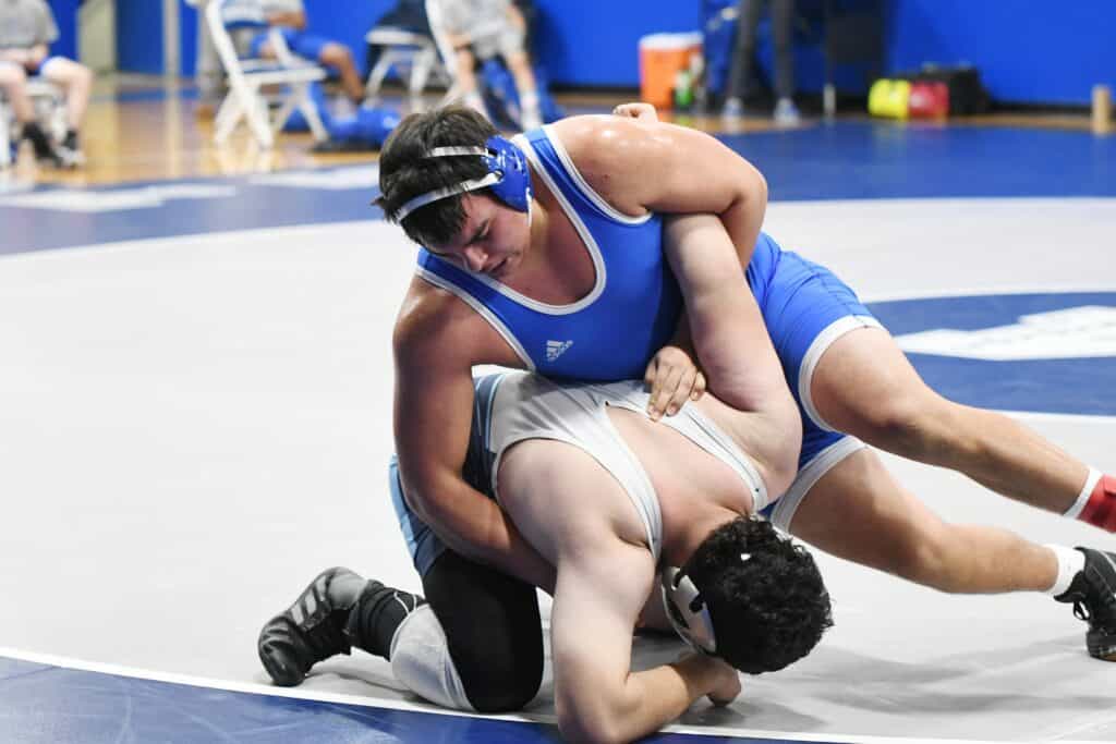 Wrestlers competing in a match at Madera gym, showcasing strength and technique.