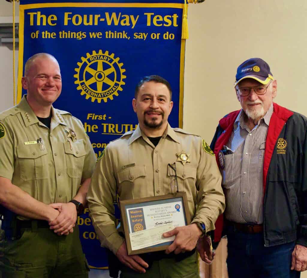 Photo of Madera County Sheriff’s Office Deputy Ronald Aguilar holds a certificate after he was honored by the Madera Sunrise Rotary. With Aguilar are Madera County Sheriff Tyson Pogue, left, and Rotary member Gordon Kennedy, right.