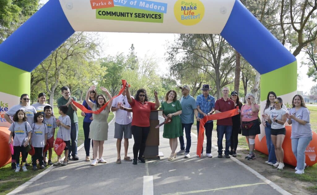 Photo of Local dignitaries and city officials gather with community members for a ribbon cutting ceremony for the newly paved and improved walking trail in Lions Town and Country Park on Saturday.