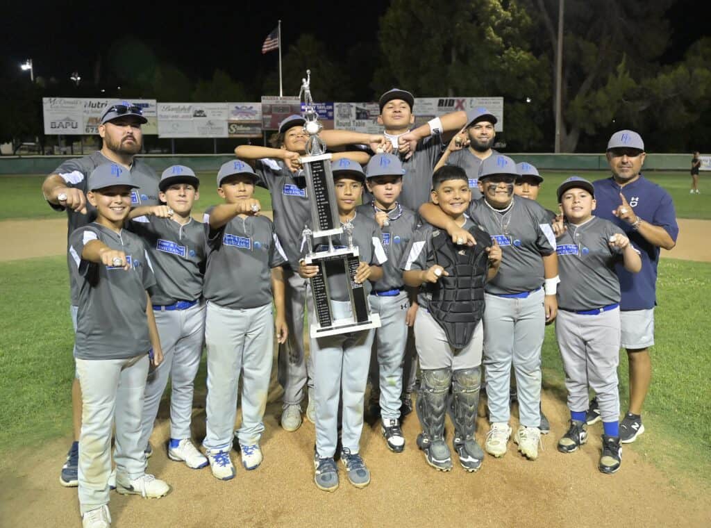 Photo - Madera National Little League’s Foster and Parker Insurance holds up the Cecil Cox Trophy and show off their rings after winning the Madera City Championship over Morgan’s Garage on Saturday.