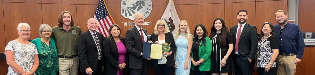 Photo - Lois Leonard poses with staff from the EDC, the Board of Supervisors, and friends as she accepts her recognition for 24 years of service.