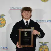 An enthusiastic Madera FFA member holding a plaque at the awards ceremony.