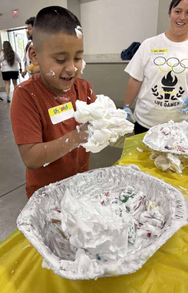 Photo - Students enjoy playing with shaving cream as one of the many booths in the sensory station.