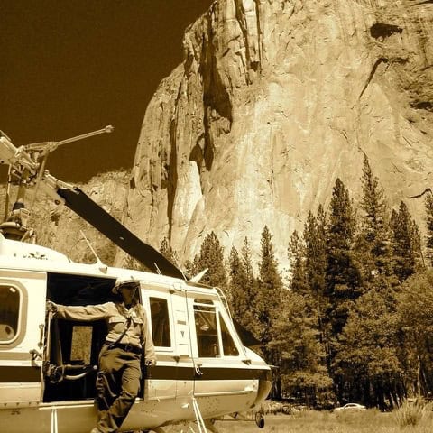 Yosemite firefighter in uniform on helicopter rescue in forested Yosemite area.