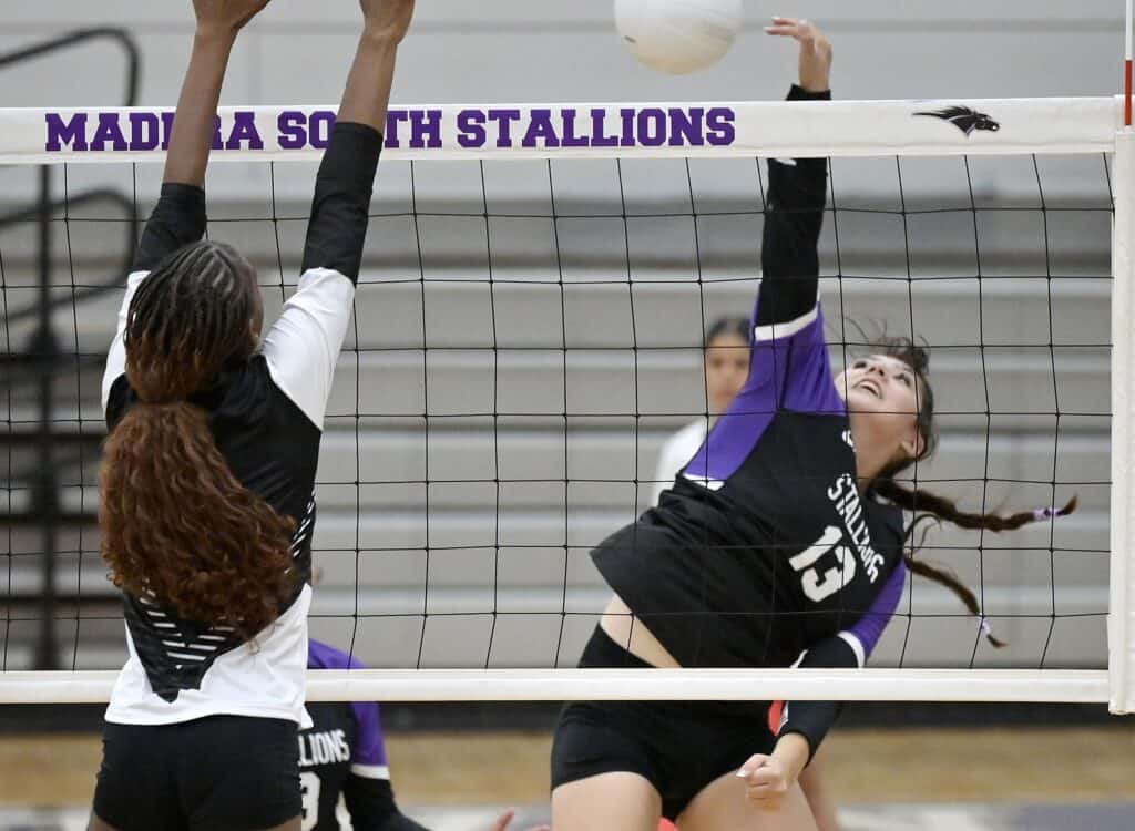 Madera South volleyball player attempts to block at the net during a match.