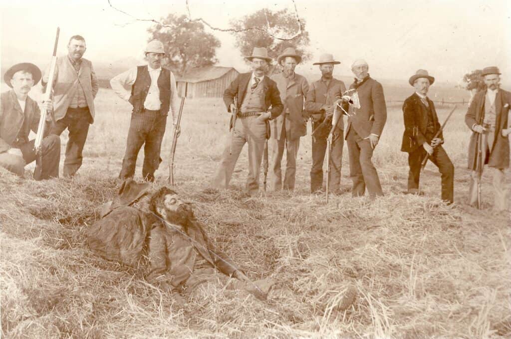 Historic photo of a stagecoach driver turned bounty hunter with a group of men in an open field.