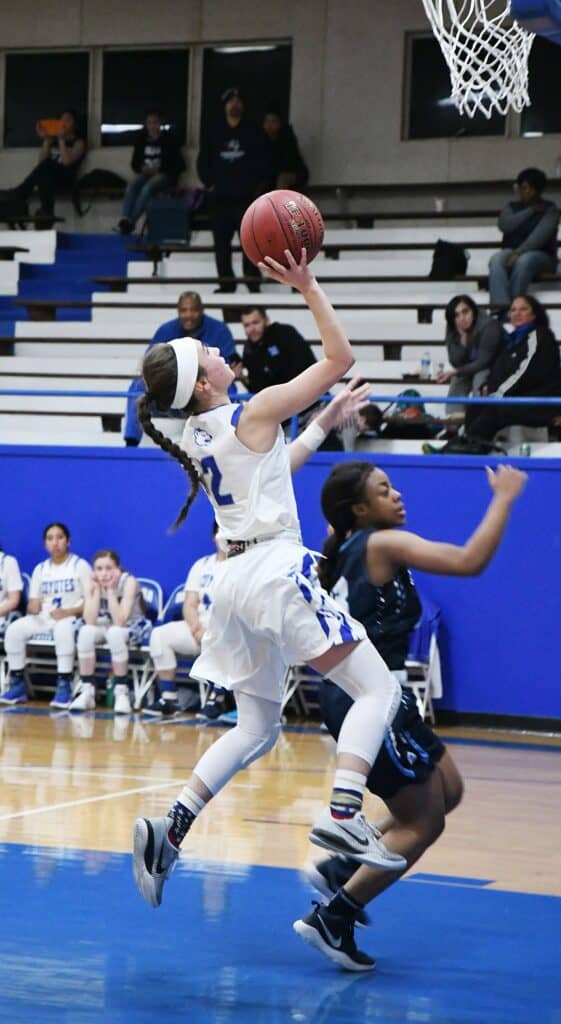 Female basketball player jumping for a shot during a game.