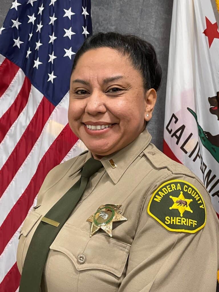 Sheriff Seaborn in uniform with Madera County Sheriff badge and flags in background.