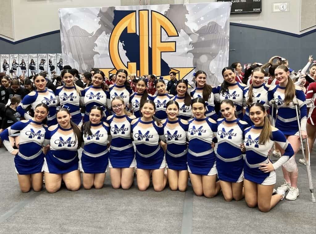 Cheerleaders in blue and white uniforms posing at MUSD cheer fundraiser event.