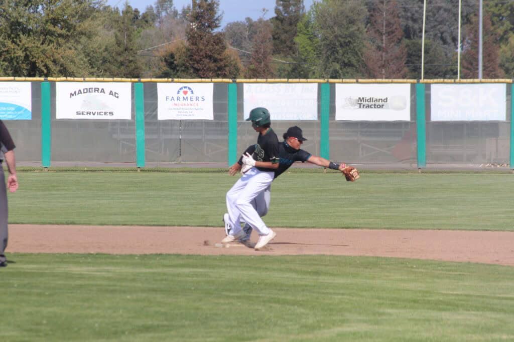 Young baseball player sliding into base during a game at Madera field.
