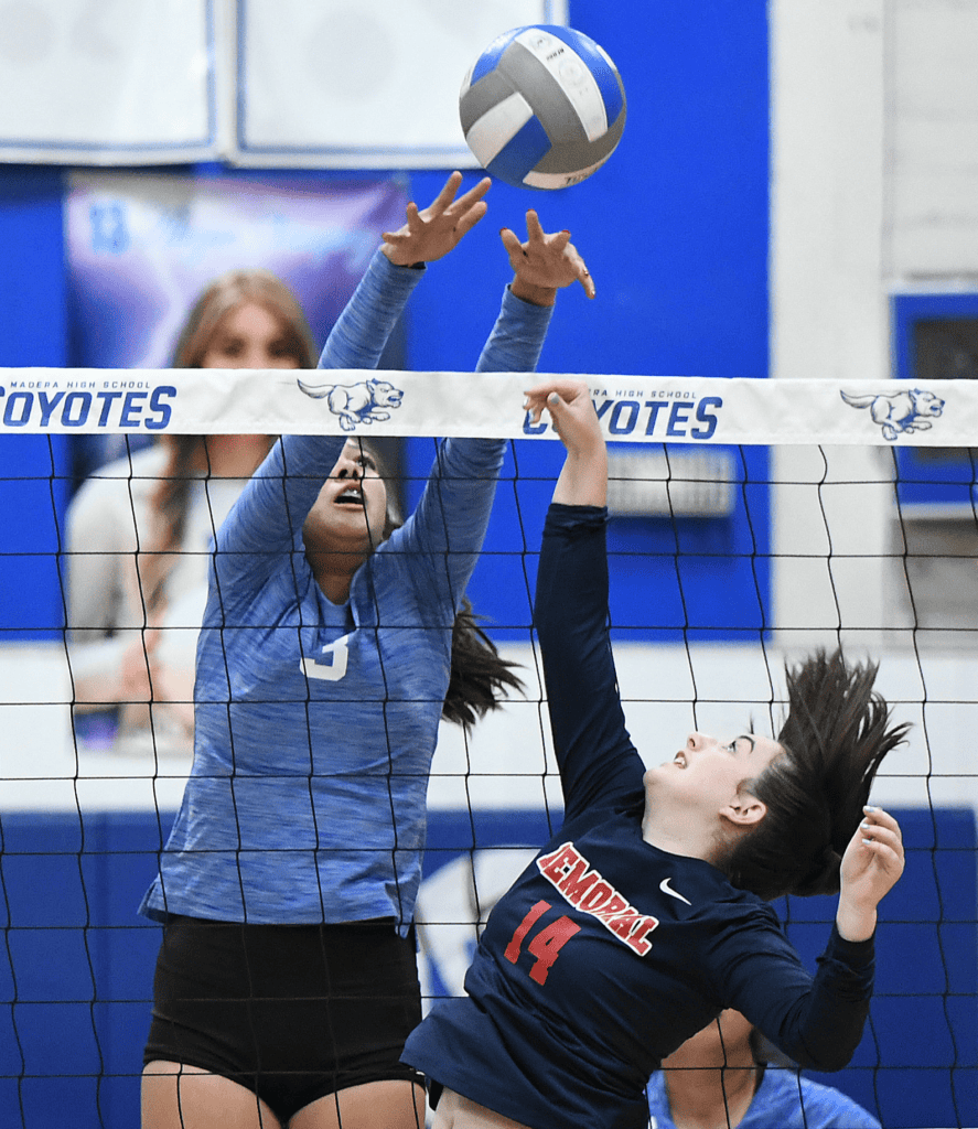 Female volleyball player jumping to hit the ball at a match.
