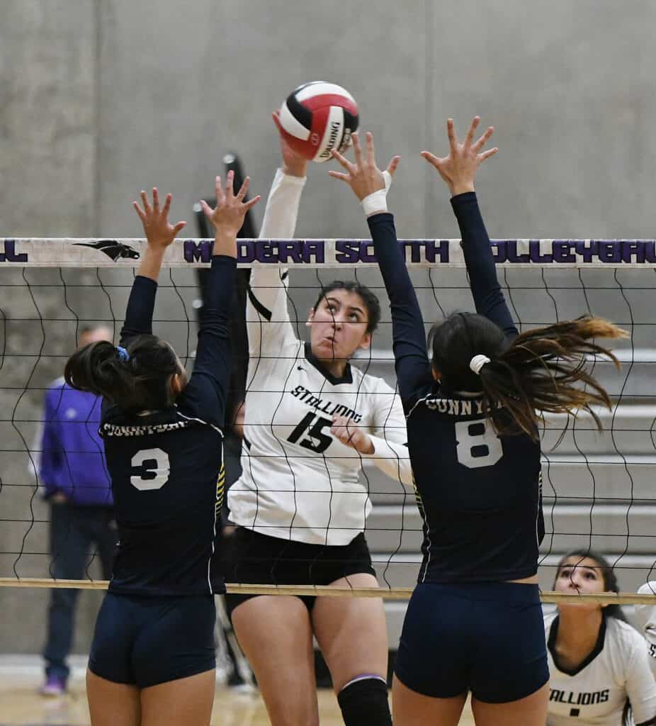 Female volleyball player spiking the ball against opponents at Madera High School.