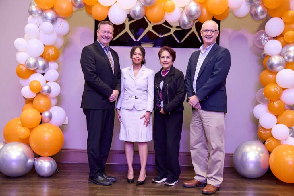 Four individuals at award event under balloon arch in Fresno and Madera Counties.