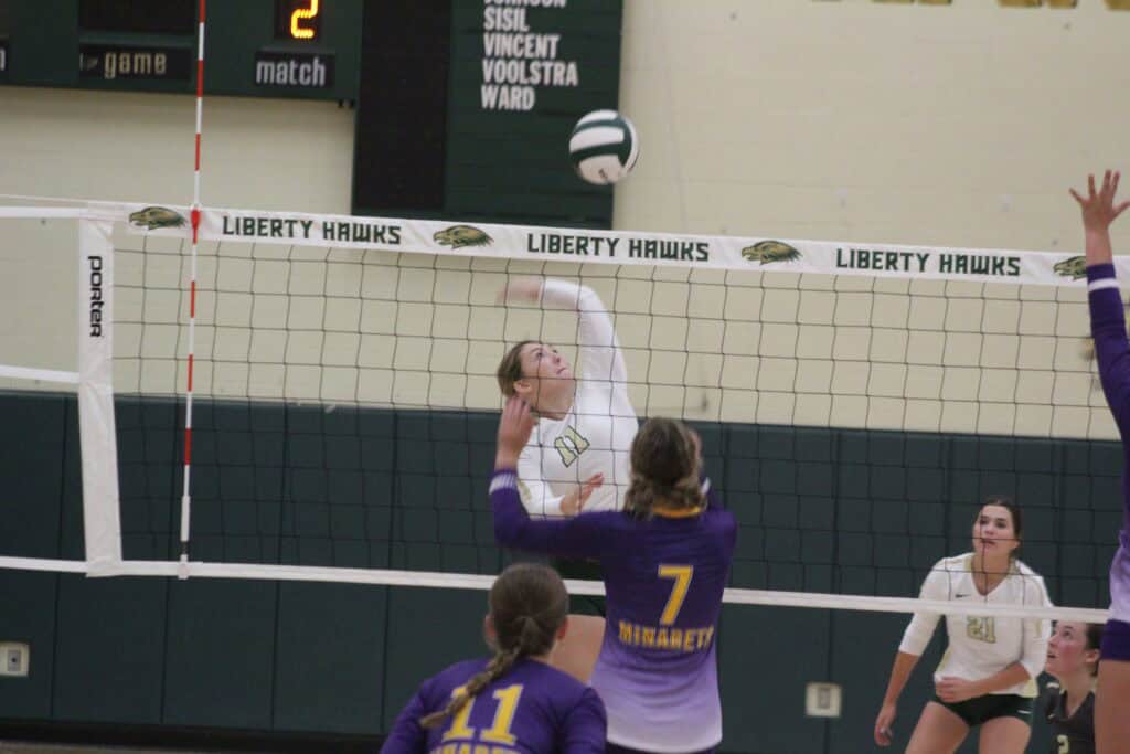 Liberty Hawks volleyball player spikes the ball during a five-set match victory.