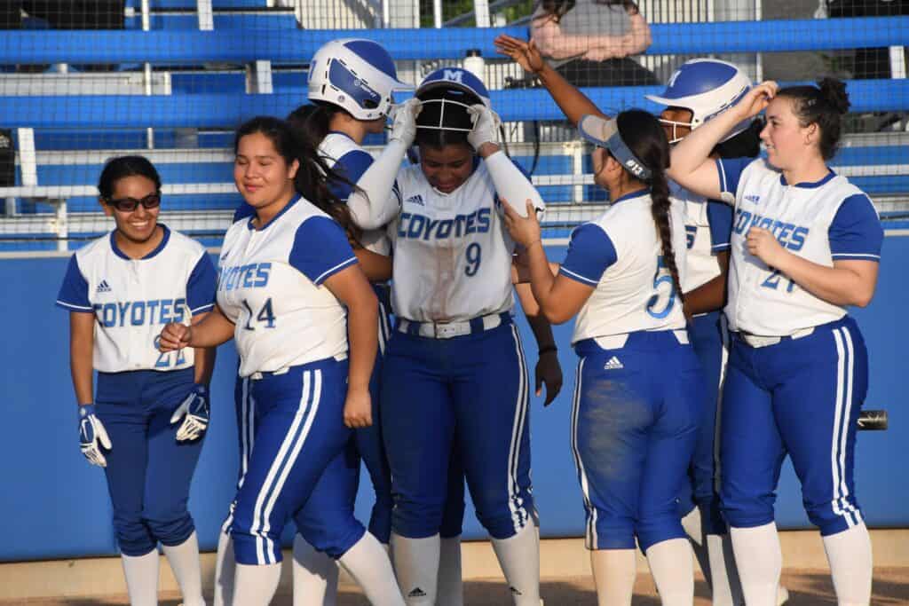 Madera Coyotes softball players celebrating after scoring runs.