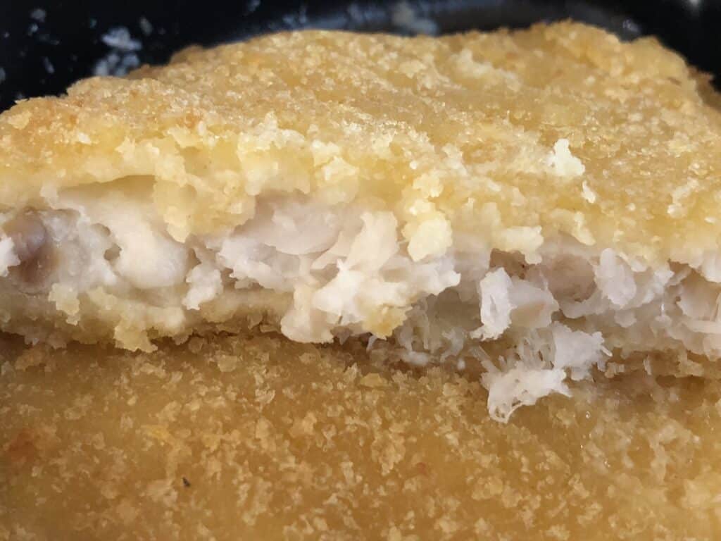 Crispy fried fish fillet with flaky white fish inside, golden breaded crust.