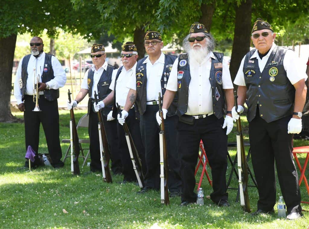 Veterans standing in a line during Memorial Day tribute in a park.