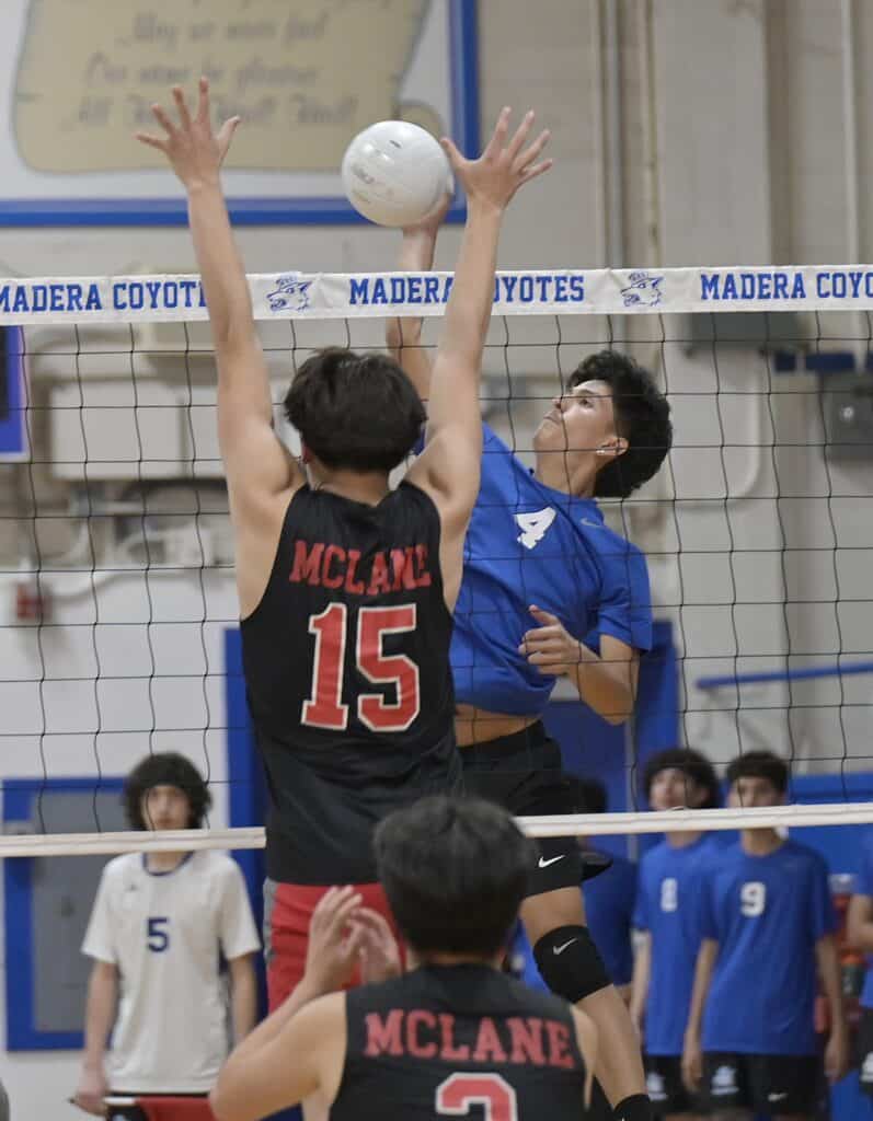 Volleyball players from Madera Coyotes and McLane compete at the net during a match.