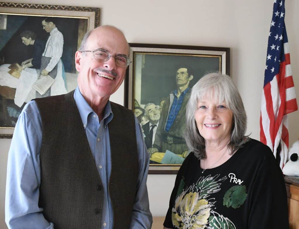 Senior man and woman smiling in an office setting.