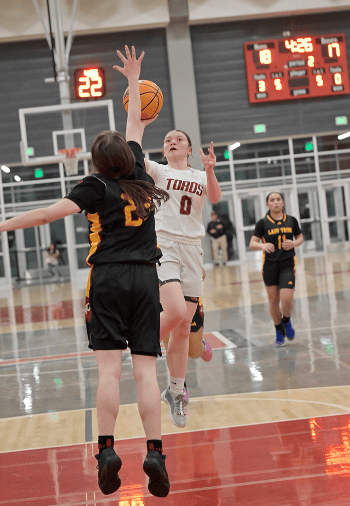 Female basketball player shooting during a high school game in the gym.