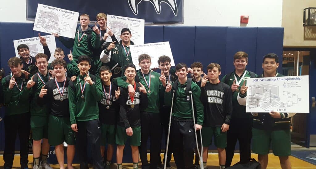 Young wrestlers holding medals and banners after winning NSL championship.
