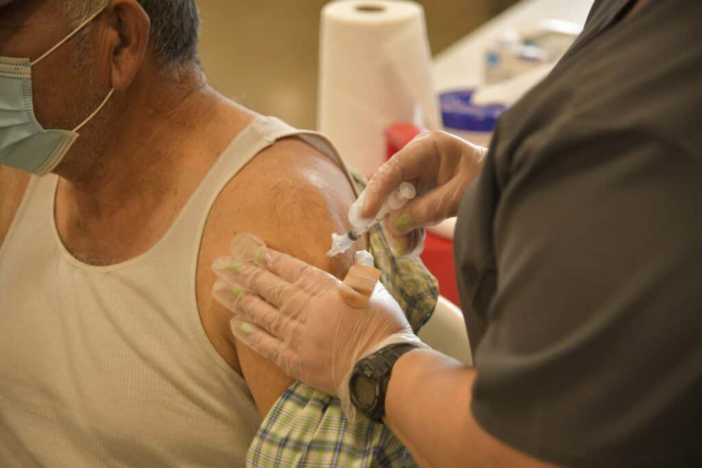 Person receiving COVID vaccine injection in arm.