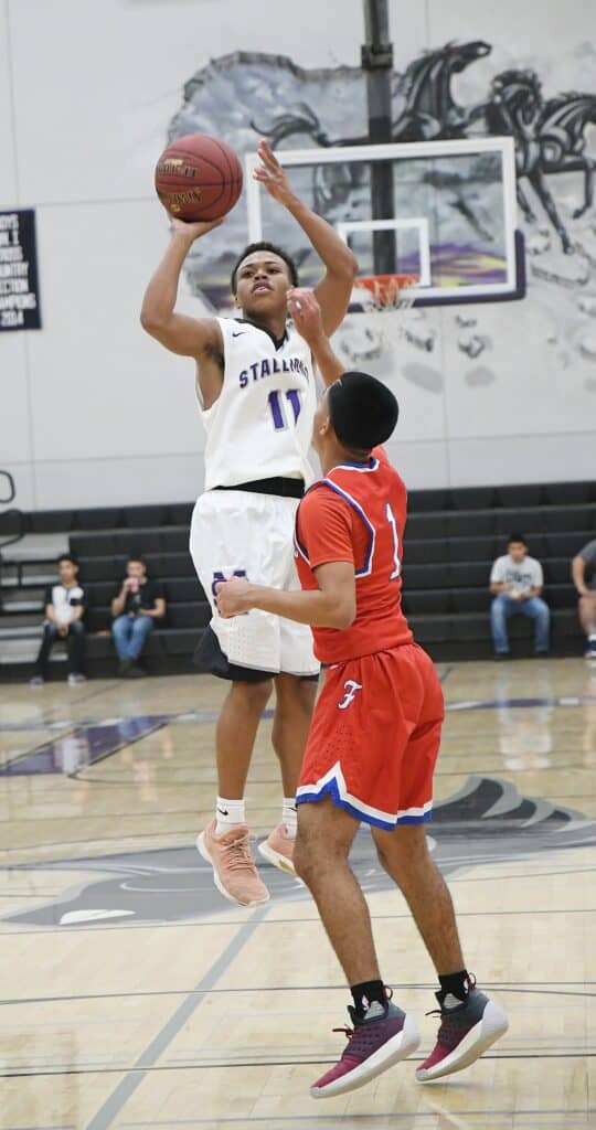 Madera Stallions player shooting basketball over defender in game.