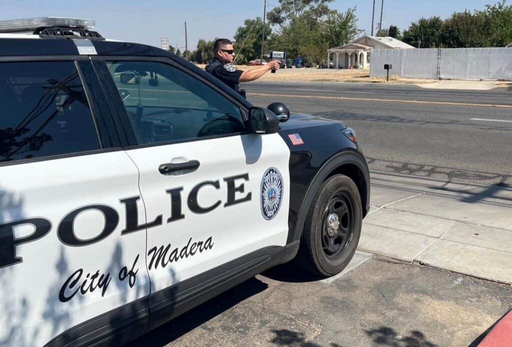 Police officer monitoring traffic from patrol car in Madera.