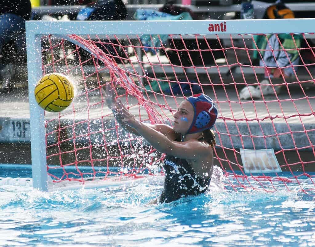 Water polo goalie saves shot during intense match.