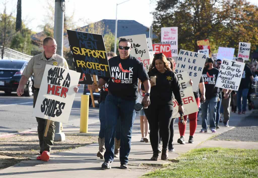 People participating in the Walk a Mile event holding signs for support and protection.