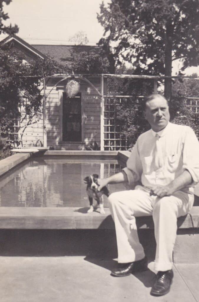Man sitting by backyard pool with dog, summer in Madera.
