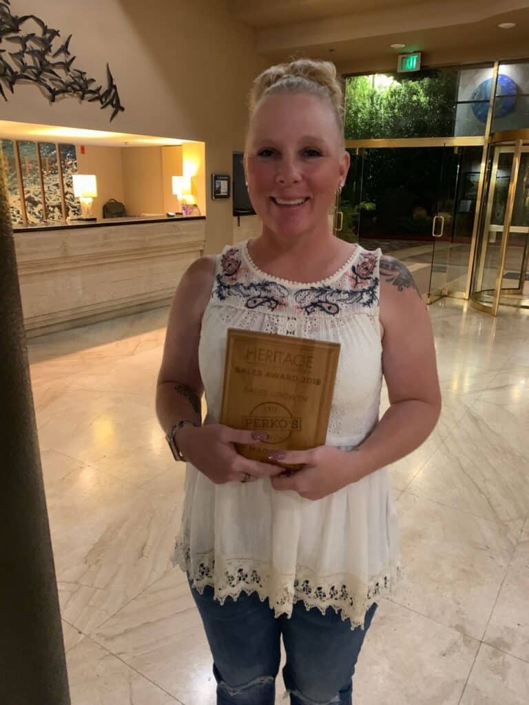 Award-winning woman holding plaque at event.