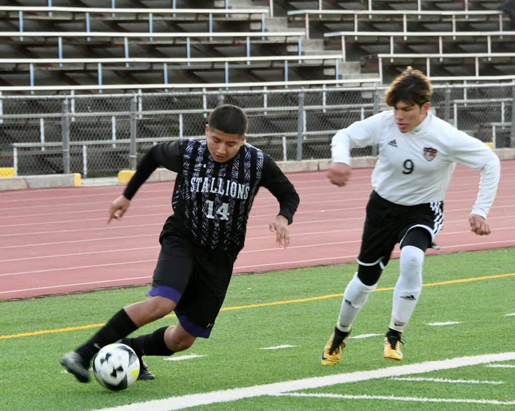 Two young soccer players competing on the field before CMAC opener.