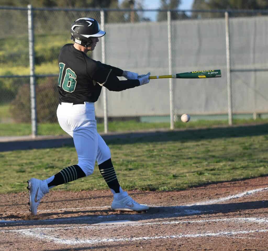 Young baseball player swinging at a pitch during a game.