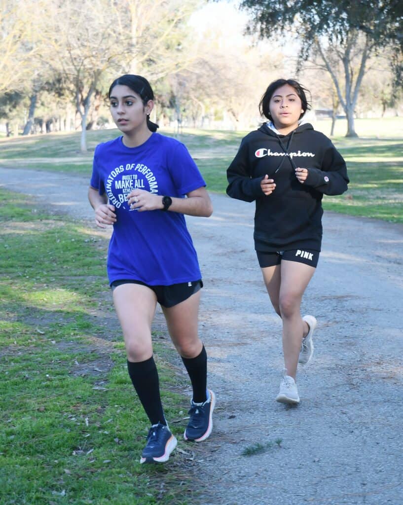 Young girls jogging in a park during daytime for a school event.