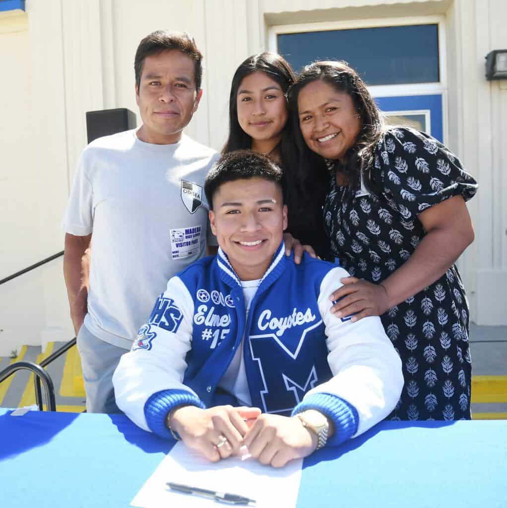 Young soccer player signing autographs at community event.
