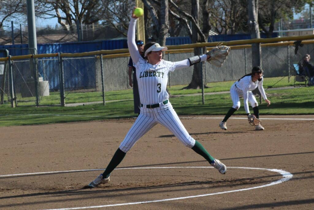 Madera softball player in action during game, preparing to catch the ball.