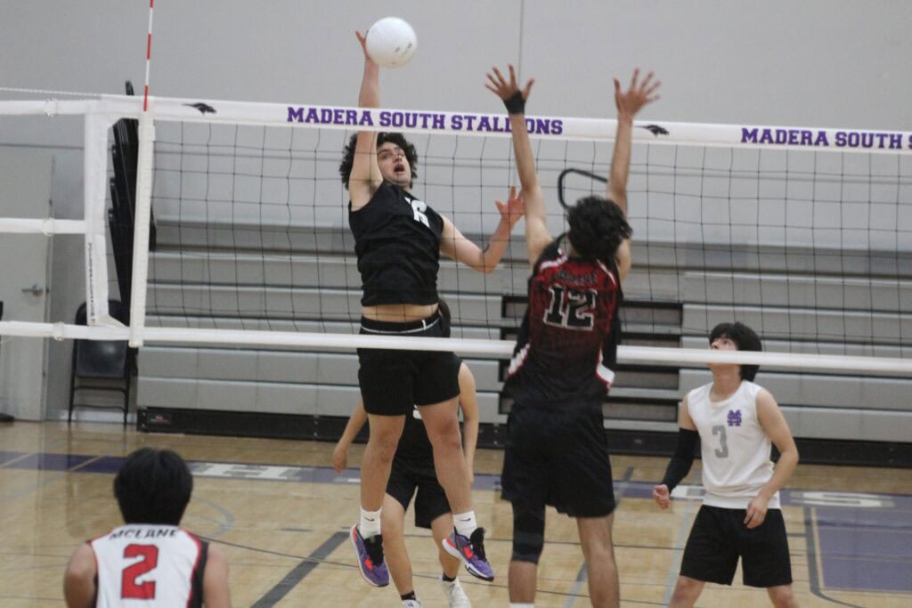 Madera South volleyball player spikes the ball against Highlanders' block.