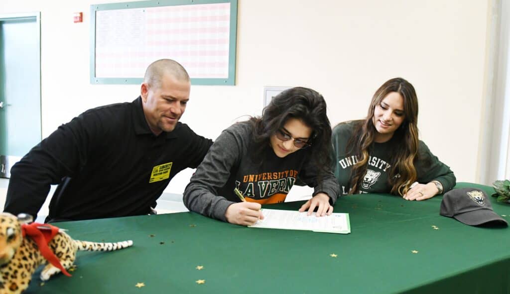 Student signing document at University of La Verne with Madera Tribune coverage.