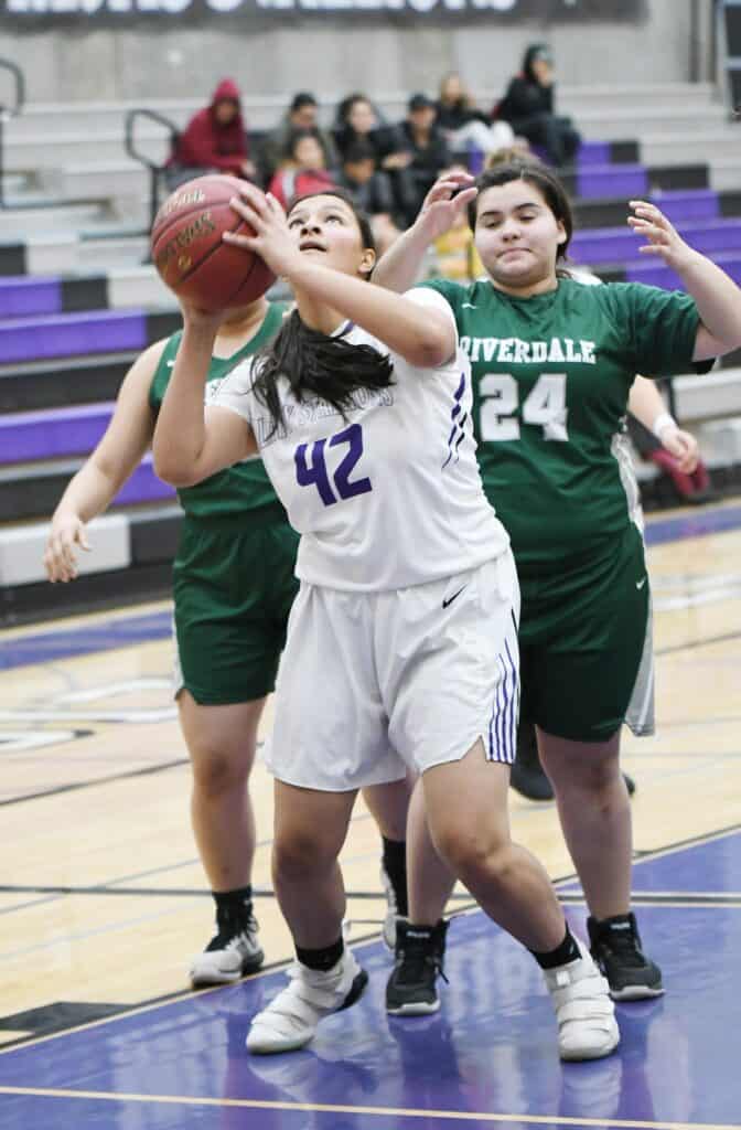 Young female basketball player shooting during game.